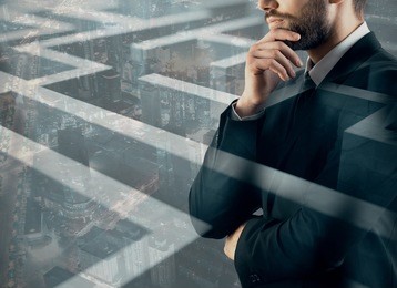 thoughtful young businessman on abstract city background with maze, labyrinth. solution concept. double exposure 