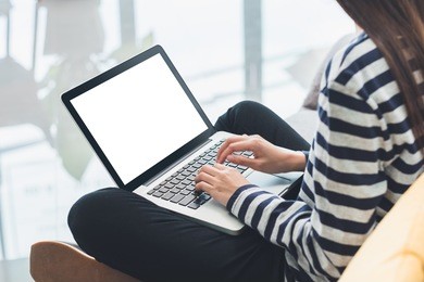 woman in casual cloth cross leg sitting on sofa and using laptop computer with blank screen,