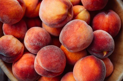 a group of ripe peaches in a bowl
