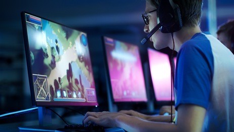 team of professional esport gamers playing in competitive  mmorpg/ strategy video game on a cyber games tournament. they talk to each other into microphones. arena looks cool with neon lights.