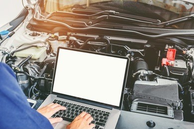 professional car mechanic working in auto repair service using laptop bon car