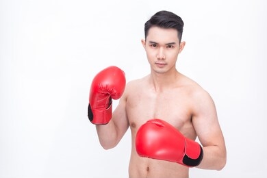 young handsome man or healthy asian boxer or thai boxer with six pack wearing boxing gloves or mitt isolated on white background
