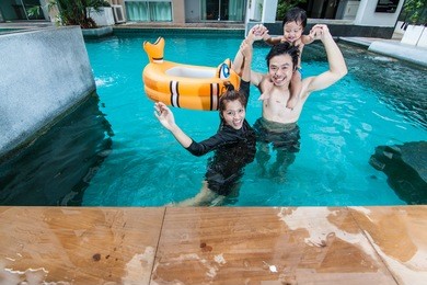 the family having fun together in swimming pool at condominium