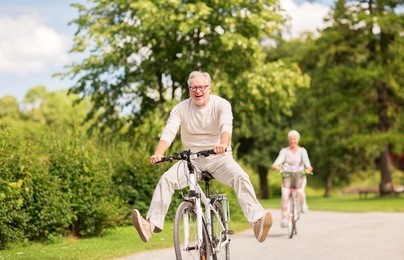 active old age, people and lifestyle concept - happy senior couple riding bicycles at summer park