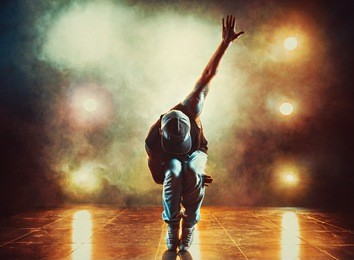 young man break dancing in club with lights and smoke. tattoo on body.