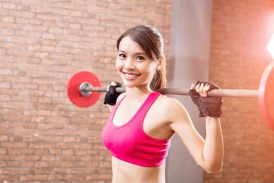 woman training hard with barbell in the gym