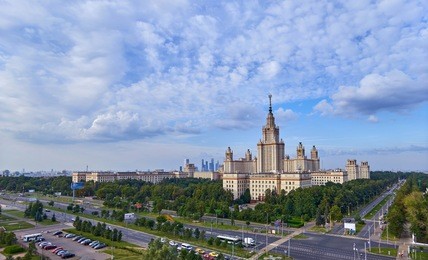 wide angle panoramic landscape view of dramatic clouds over the sunny summer campus of lomonosov moscow state university under blue sky