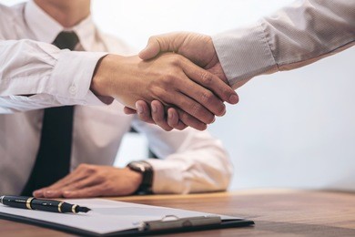 real estate broker agent and customer shaking hands after signing contract documents for realty purchase, bank employees congratulate, concept mortgage loan approval.