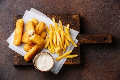fish fingers and chips british fast food with tartar sauce on dark background