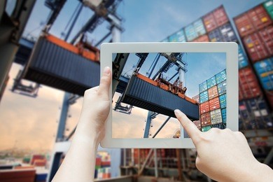 businessman use tablet for industrial crane loading containers in a cargo freight ship, technology for business management, hand use ar application in tablet or smartphone