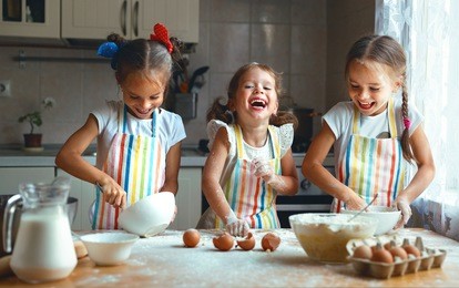 happy sisters children girls bake cookies, knead dough, play with flour and laugh in the kitchen
