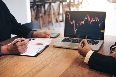business team two colleagues working with computer, digital tablet, discussing and analysis graph stock market trading with stock chart data, financial and investment concept.