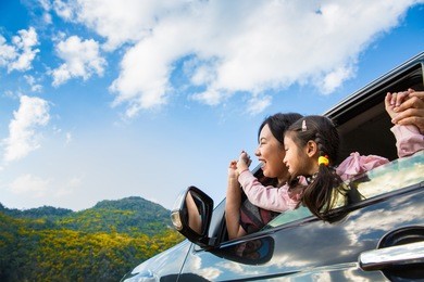 asian mother and daughter enjoy travel in a car with mountain background