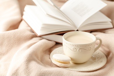 cup of hot tea with lemon dressed in knitted warm winter scarf on wool, soft focus