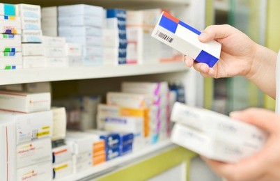 pharmacist holding medicine box in pharmacy drugstore.