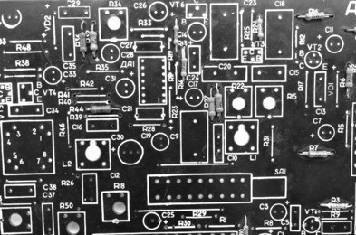 old circuit board with inscriptions and markings under the components, closeup, background, black and white
