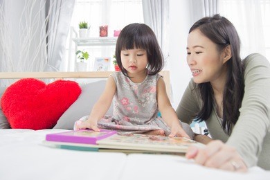 pretty young mother reading a book to her daughter.