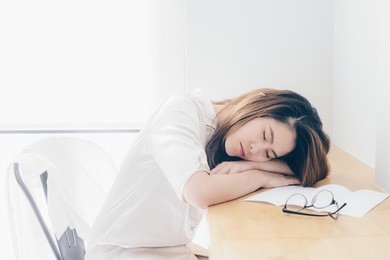 portrait of asian woman sleeping on the desk after her work overtime.