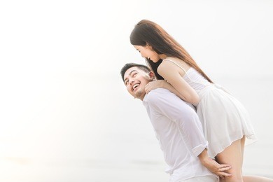 couple in love. couple on the beach. smiling couple holding hands on the beach. asian woman, caucasian man. travel vacation retirement lifestyle concept.