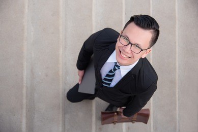 top view of handsome asian businessman wearing black suit smiling while walking up the stairs 