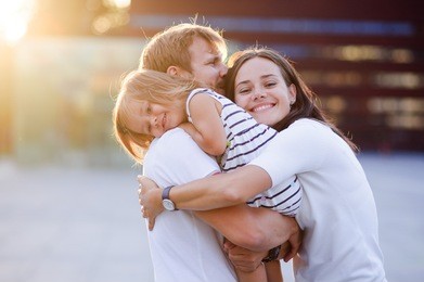 portrait of a young united family. father keeps a small daughter in his arms. woman gently embraces husband and daughter.