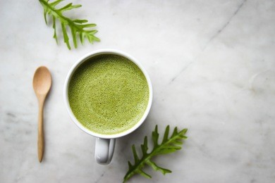 hot green tea latte  with green leaves and wooden spoon