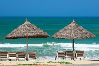 beach umbrellas and deck chairs in front of the my khe beach in da nang, vietnam.