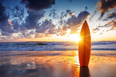surfboard on the beach at sunset