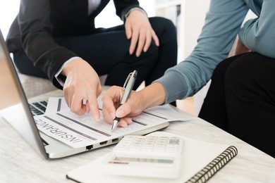 closeup photo of female customer fill in personal information on insurance document.