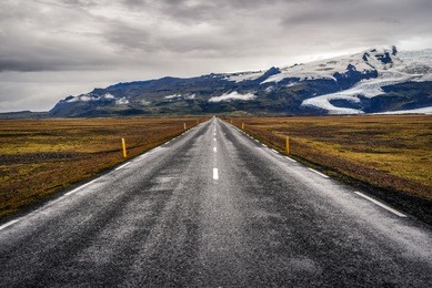 road in iceland, asphalt and mountains with a glacier in the background.