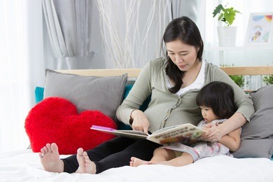 pretty young mother reading a book to her daughter.