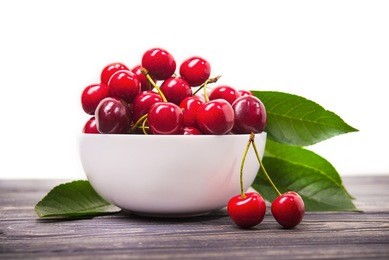 fresh red cherry fruit in plate on wood table isolated on white background