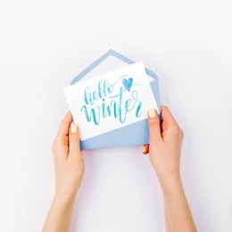 woman holding card with word hello winter. flat lay, top view