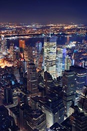 new york city manhattan times square panorama aerial view at night with office building skyscrapers skyline illuminated by hudson river.