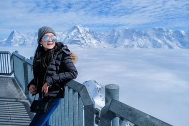 young woman tourist at the schilthorn in switzerland with a magnificent panoramic view of the swiss skyline. 