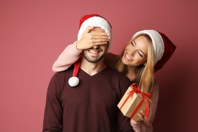 young woman giving her boyfriend christmas present, on color background
