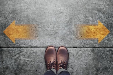 making decision concept, top view of male with leather shoes with arrow left and right present over grunge cement concrete crossroad background