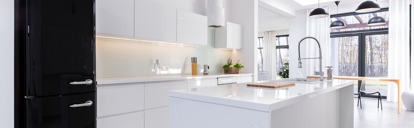 panorama of white open kitchen with black fridge and built-in modern cabinets