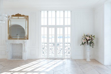 chic white huge spacious hall with a minimum of expensive antique furniture. baroque interior design with ornament on the walls and parquet on the floor.