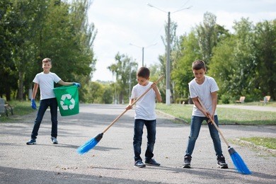 volunteering, charity, cleaning, people, children and ecology concept - group of happy volunteers with garbage bags walking in park. outdoors photo. environmental protection concept.