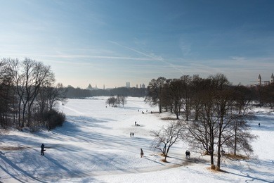 panoramic view of english garden covered in snow and munich skyline on a sunny winter day