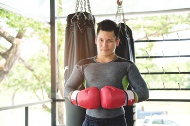 asian handsome sportman who has perfect body exercise by boxing with red boxing gloves at gym,box fighters training sport concept