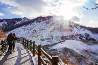 traveler walking into jigokudani, known in english as "hell valley" is the source of hot springs for many local onsen spas in noboribetsu, hokkaido, japan.