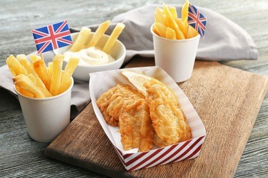 tasty fried fish and potato chips on wooden table