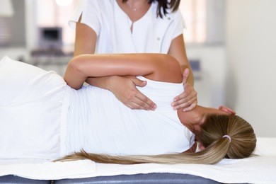 professional female physiotherapist giving shoulder massage to