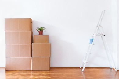 stack of cardboard boxes with ladder in empty room. copy space.