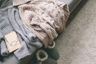 cashmere sweater and reading on gray sofa. warm weekend at home. detail of cozy winter interior.