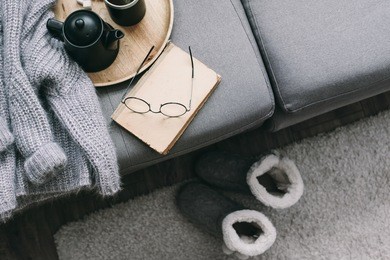 cashmere sweater, reading and serving tray on gray sofa. warm weekend at home. detail of cozy winter interior.