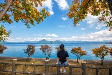 young woman is sitting at lake toya in shikotsu-toya national park, hokkaido, japan
