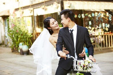 romantic asian newly wed couple having fun riding a bicycle together.